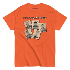Puede incluir: Camiseta naranja con la inscripción "THE SKYLINE BOYS" sobre cinco retratos en blanco y negro de hombres. Cada retrato tiene una etiqueta con un nombre. La camiseta es de cuello redondo.