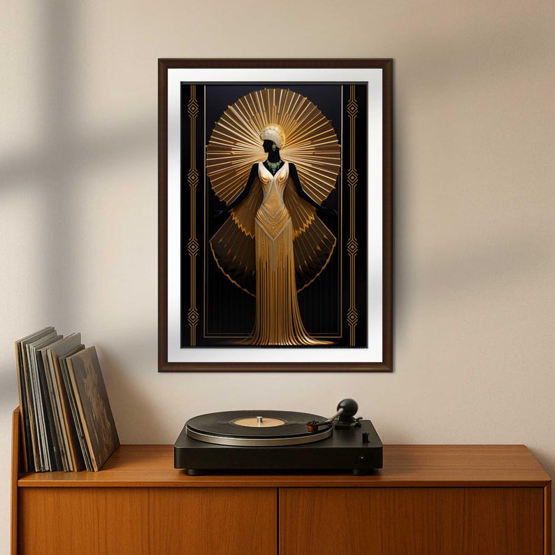 May include: Art Deco style framed print featuring a gold-colored figure in a flowing gown with outstretched wings, set against a black background with a golden sunburst design. The figure has a white headpiece and a green necklace. The frame is brown.