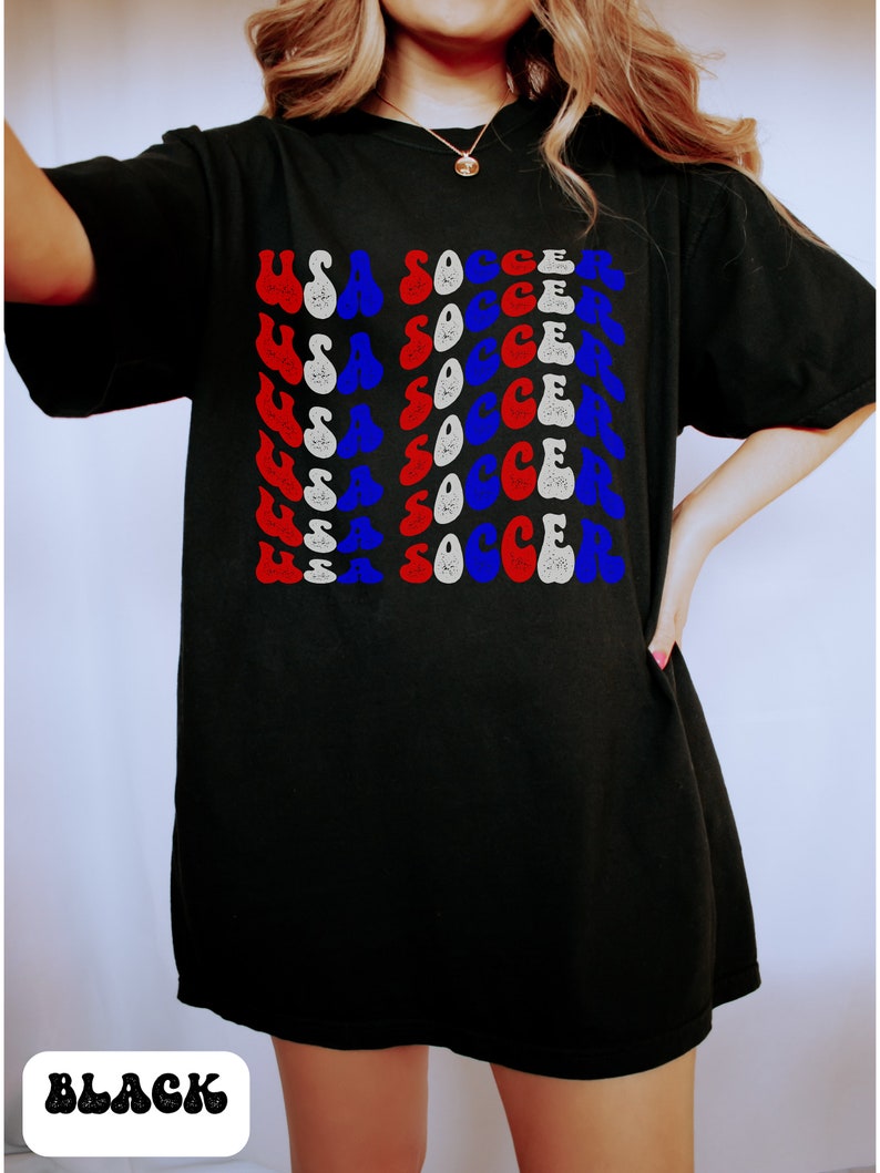 May include: Black t-shirt with a graphic print of "USA SOCCER" repeated in red, white, and blue.