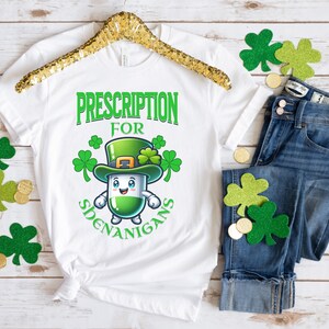 May include: White t-shirt with a green cartoon pill wearing a green leprechaun hat and the text "Prescription for Shenanigans".