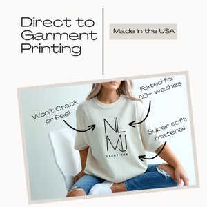 May include: A white t-shirt with the text "NL MJ CREATIONS" printed on the front. The shirt is made in the USA and is rated for 50+ washes. The text "Won't Crack or Peel" is written on the left side of the image and "Super soft material" is written on the right side of the image.