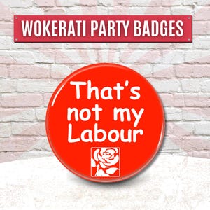 May include: A red badge with the text "That's not my Labour" in white, and a white rose emblem. The badge is set against a brick wall background, with a sign above that reads "Wokerati Party Badges".