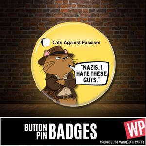 May include: A round yellow button pin featuring a cartoon cat dressed as an adventurer with a brown hat and jacket. The text reads "Cats Against Fascism" and a speech bubble says "NAZIS. I HATE THESE GUYS." The design includes a small whip.
