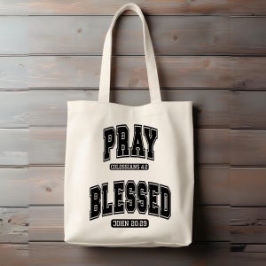 Pode incluir: Saco tote creme com texto preto que diz "PRAY" acima de "COLOSSIANS 4:2" e "BLESSED" acima de "JOHN 20:29". O saco tem duas al&ccedil;as e est&aacute; pendurado em um fundo de madeira.
