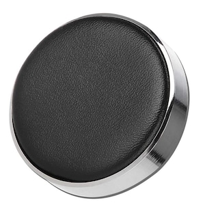 May include: A round, black leather watch cushion with a silver metal rim. The cushion is designed to protect and display watches.