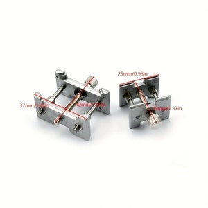 K&ouml;nnte beinhalten: Zwei silberfarbene Metallklemmen mit verstellbaren Schrauben. Eine Klemme misst 37mm in der L&auml;nge, 42mm in der Breite, die andere 25mm. Sie dienen dazu, Objekte zusammenzuhalten. Die Ma&szlig;e sind in mm und Zoll angegeben.