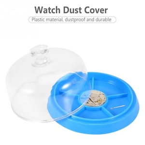 May include: A clear plastic dome dust cover for a watch repair kit. The kit has a blue base with compartments and a watch movement inside.