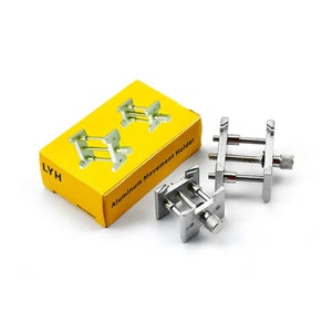 May include: A collection of silver-coloured aluminium watch movement holders, alongside a yellow box. The box is labelled "LYH" and "Aluminum Movement Holder". The holders feature adjustable screws, designed for watch repair.