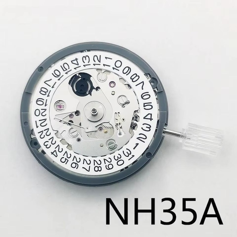 K&ouml;nnte beinhalten: Ein Uhrwerk mit einem grauen Au&szlig;enring und einem wei&szlig;en Innenzifferblatt. Das Zifferblatt hat schwarze Ziffern, die das Datum und die Uhrzeit anzeigen. Der Text "NH35A" ist unten in Schwarz gedruckt. Eine transparente Kunststoffkrone ist seitlich angebracht.