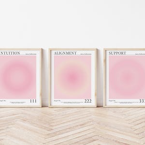 May include: Three framed prints with pink and white gradient backgrounds. The prints are titled "INTUITION", "ALIGNMENT", and "SUPPORT" with the text "Angel No." and a number below each title.