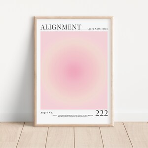 May include: A pink and white gradient poster with the text "ALIGNMENT Aura Collection" at the top and "Angel No. 222" at the bottom. The text "In our infinite alignment to our fires, we are guided by the gentle whispers of the universe." is below the number.