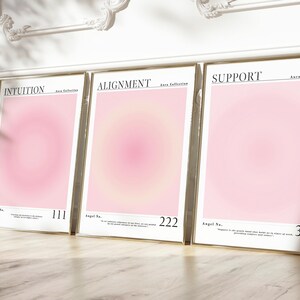 May include: Three framed pink and white gradient prints with gold frames. The prints have the words "Intuition", "Alignment", and "Support" at the top and the angel numbers 111, 222, and 333 at the bottom.