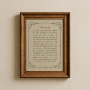 May include: A framed print displaying the text of Psalm 23. The text is in a traditional serif font, set against a light beige backdrop. The frame is a warm, medium brown, and the print is suitable for home decor.