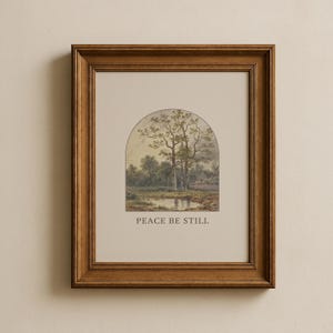 May include: A framed landscape print depicting a tranquil scene with trees, a pond, and a small building. The artwork is set within an arched shape and framed in a brown wooden frame. The text "PEACE BE STILL" is printed below the image.