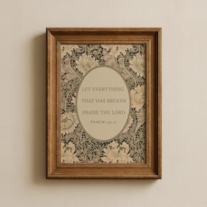 May include: A framed print with the text "LET EVERYTHING THAT HAS BREATH PRAISE THE LORD" and "PSALM 150: 6" in an oval. The background has a floral pattern in beige, black, and cream. The frame is a dark brown colour.