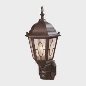 May include: A bronze outdoor wall-mounted lantern with a decorative top and textured glass panels. The lantern has an oval shape and is designed to be mounted on a wall. The fixture is made of metal and has a classic design.
