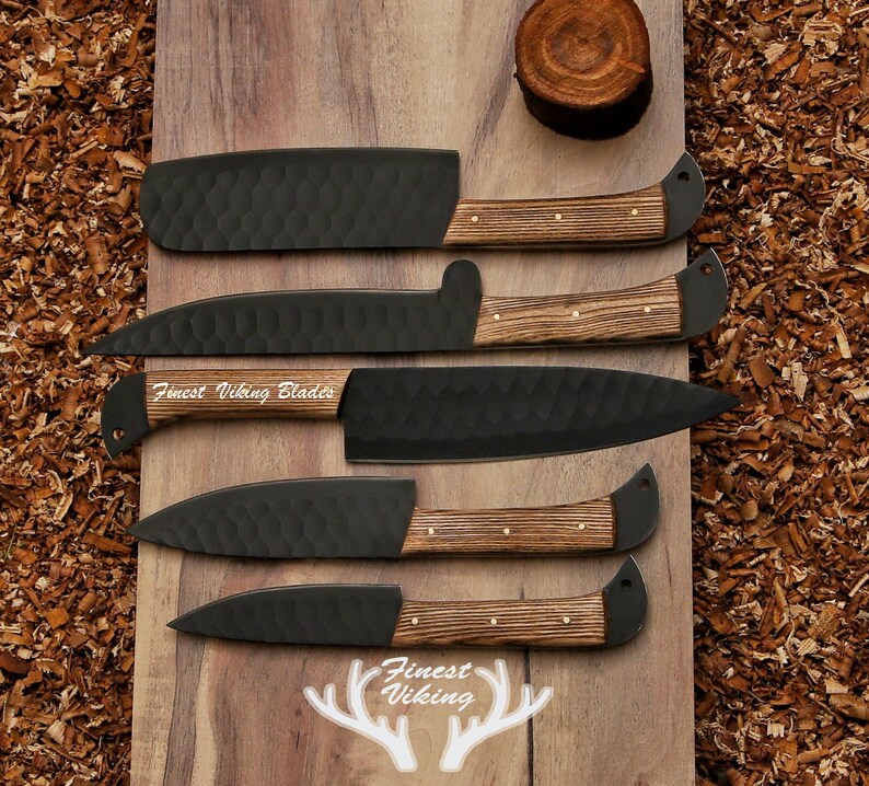 May include: Five black kitchen knives with wooden handles on a wooden surface. The knives have a hammered finish and the handles are made of dark wood with light wood accents. The knives are arranged in a row, with the largest knife at the top and the smallest knife at the bottom. The text "Finest Viking Blades" is engraved on the blade of one of the knives.