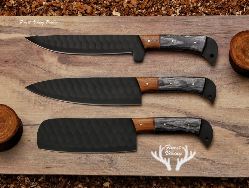 May include: Three black kitchen knives with wooden handles and a textured blade. The knives are arranged on a wooden surface. The text "Finest Viking Blades" is visible at the top of the image.
