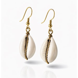 May include: A pair of seashell earrings with gold-colored hooks and wire accents. The white shells are oval-shaped and have a natural, textured appearance. The earrings are displayed against a white background.