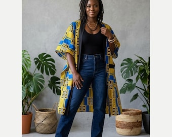 May include: A long, open-front kimono-style jacket featuring a vibrant geometric pattern in shades of mustard yellow, royal blue, and black. The garment is worn over a simple black tank top and dark blue denim jeans with brown sandals.