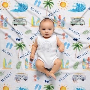 May include: A white baby blanket with a blue and white surf theme. The blanket features surfboards, palm trees, sunglasses, flip flops, and the name "MICHAEL" repeated throughout. A baby is lying on the blanket.