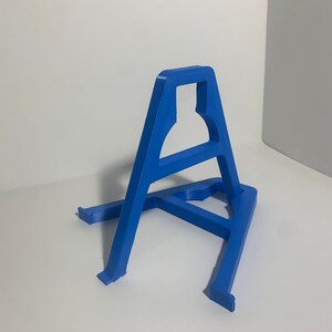 May include: A blue plastic stand for displaying items. The stand is shaped like a triangle with a small opening at the top.