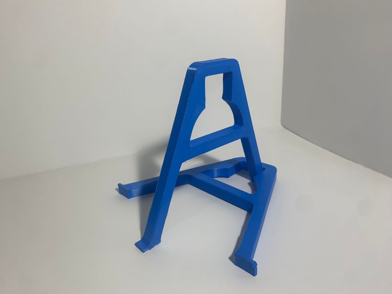 May include: A blue plastic stand for displaying items. The stand is shaped like a triangle with a small opening at the top.