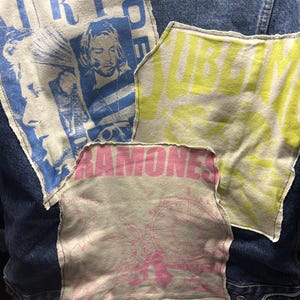 May include: A blue denim jacket with patches sewn on. The patches are made of different fabrics and feature various designs, including a band logo, a graphic of a person, and the word "Sublime".