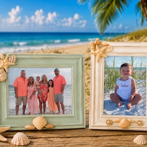 May include: Two rectangular picture frames with distressed finishes, one light green and one off-white, decorated with natural seashells and starfish. The frames hold photographs of a family and a baby, displayed on a weathered wooden surface.