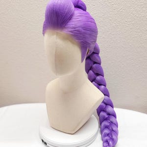 May include: A 32-inch dark purple wig styled with a high, voluminous pompadour at the front and a long, thick, single braid extending down the back. The wig is displayed on a mannequin head and features the text 32" Dark Purple w/ Tulle.
