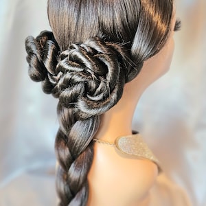 May include: A dark brown wig styled with two intricate, rose-shaped buns positioned at the back of the head. The hair is smooth and glossy, featuring a long, thick, three-strand braid that extends downward from the base of the styled buns.