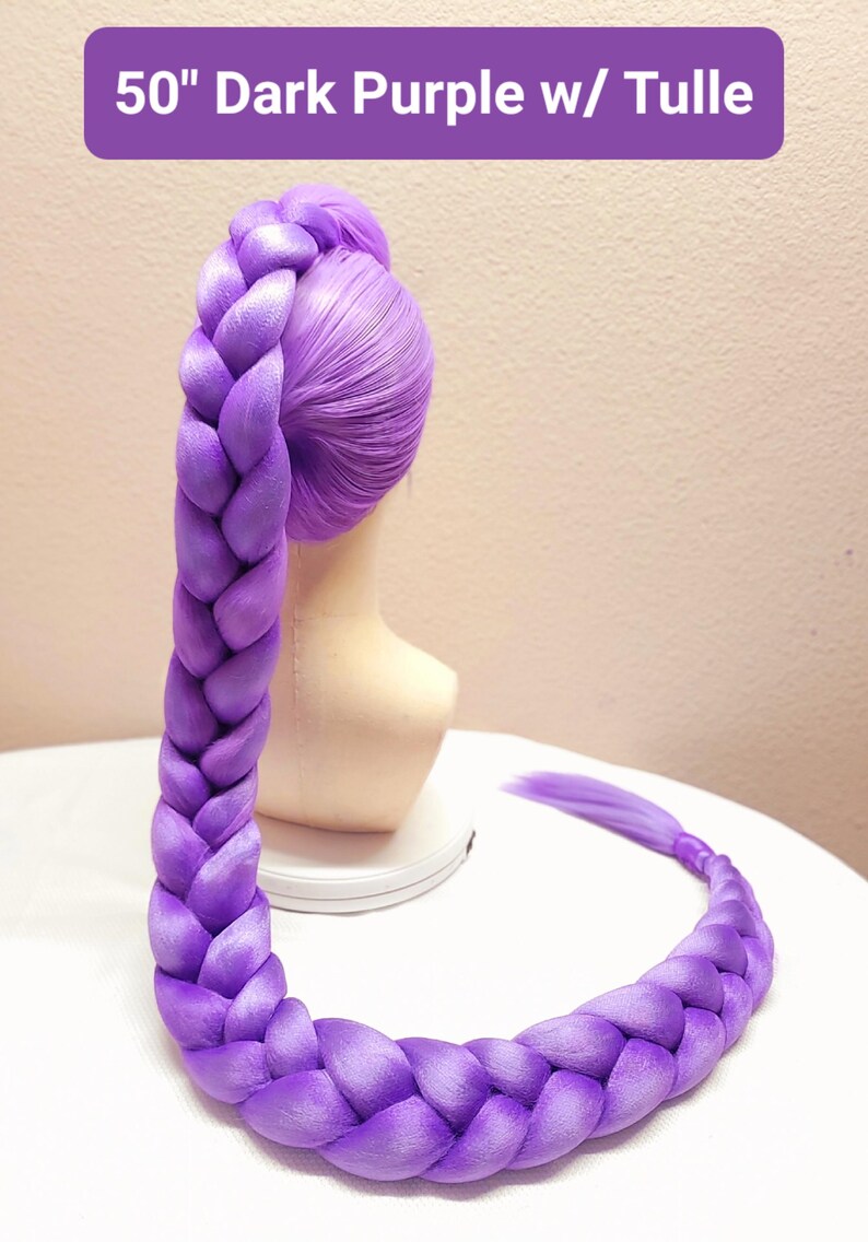 May include: A 50-inch dark purple wig styled in a long, thick, single braid that extends from the crown of the head down to the base. The wig features a smooth, vibrant purple fiber texture and includes tulle detailing at the top attachment point.