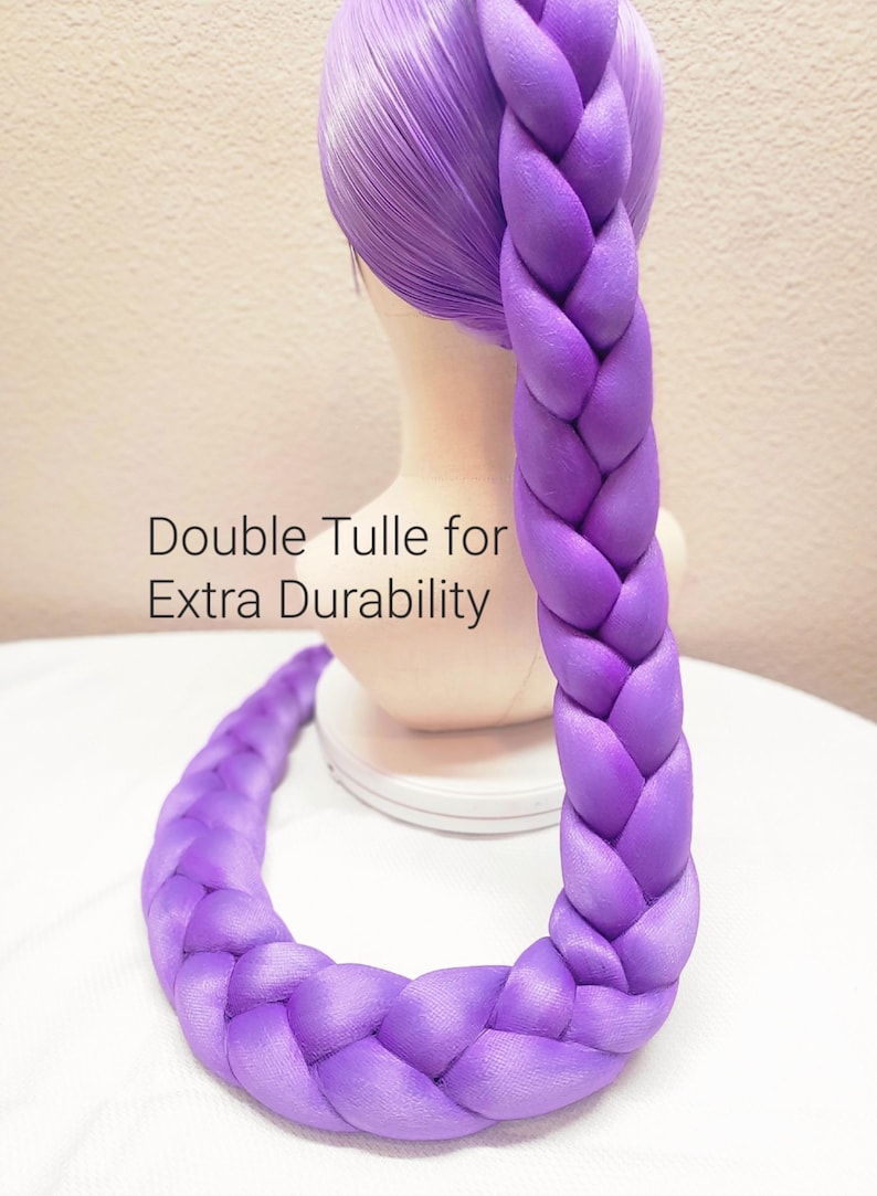 May include: A bright purple wig styled with a long, thick, single braid that extends downward. The wig is displayed on a mannequin head. Text on the image reads: Double Tulle for Extra Durability. The hair has a smooth, synthetic texture.