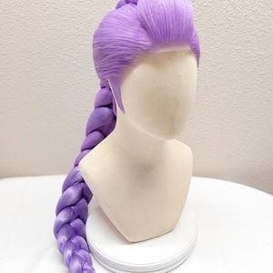 May include: A 32-inch light purple wig styled with a voluminous top section and a long, thick, single braid that extends down the back. The wig features a sheer tulle lace front hairline and is displayed on a neutral-colored mannequin head.
