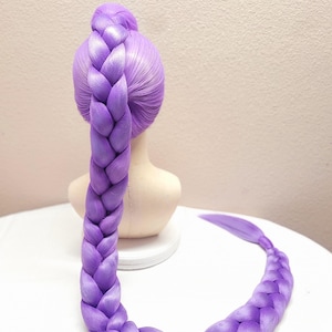 May include: A 50-inch light purple braided hair extension styled in a high ponytail on a mannequin head. The braid is thick and long, extending downward and curving across the surface. The text 50" Light Purple w/ Tulle is visible at the top.