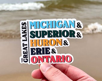 May include: A white sticker with the text "The Great Lakes" vertically on the left side and the text "Michigan & Superior & Huron & Erie & Ontario" vertically on the right side. The text is in a rainbow of colors.