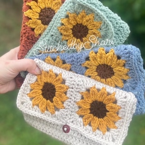Puede incluir: Tres bolsas de ganchillo con forma de girasol en diferentes colores: naranja, azul y beige. La bolsa beige tiene un cierre de botón y el texto "Stitched by Shari" es visible en la bolsa azul.