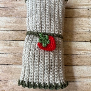May include: A crocheted gray and green utensil holder with a red and green strawberry applique.