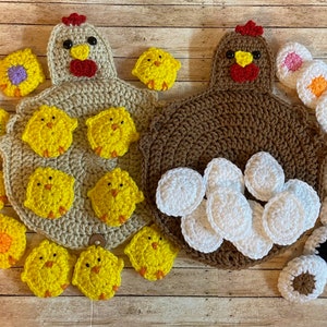 May include: Two crocheted chicken-shaped pot holders, one brown and one beige, with crocheted chicks and eggs surrounding them. The brown chicken has white eggs, and the beige chicken has yellow chicks.