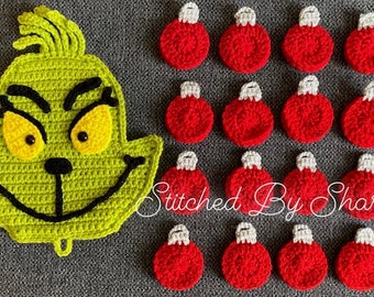 May include: Green crocheted Grinch face with yellow eyes and a black mouth.  There are 15 red crocheted ornaments with white tops.