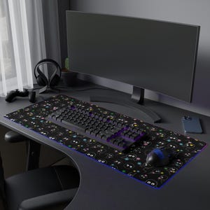 Può includere: Un tappetino per mouse da gioco nero con un design di cartoni animati colorati. Il tappetino per mouse include una tastiera nera e un mouse da gioco nero con una luce viola.