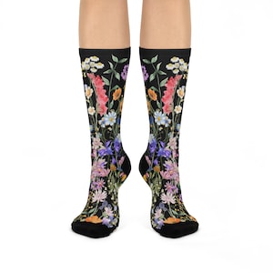 May include: A pair of black socks featuring a vibrant floral design. The socks display a variety of colorful flowers, including pink, orange, blue, and purple, set against a black background. The socks are knee-high.