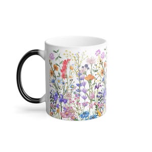 May include: A white ceramic mug with a black handle. The mug features a colorful floral design with a variety of flowers and leaves.