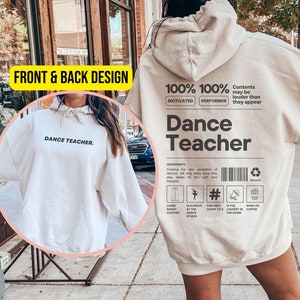 Könnte beinhalten: Ein beiger Hoodie mit einer Fronttasche und einer Kapuze. Die Vorderseite des Hoodies trägt den Schriftzug "Dance Teacher". Die Rückseite des Hoodies trägt den Schriftzug "100% Motivated 100% Performer" und "Dance Teacher". Die Rückseite des Hoodies enthält außerdem eine Liste von Zutaten für einen Tanzlehrer, darunter "Liebt weite Kleidung", "Ist immer im Tanzstudio", "Kann nur bis 8 zählen", "Ist der Lauteste im Raum" und "Läuft mit Kaffee."