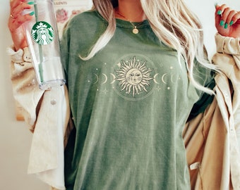 Op de afbeelding: Een groen T-shirt met een vintage-zon en maan motief. Het motief toont een zon met een gezicht en stralen, en een wassende maan. Het shirt heeft een verweerde look en is gemaakt van een zachte, comfortabele stof.