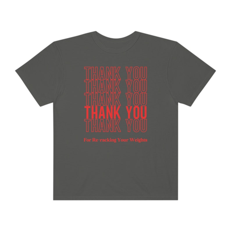 Peut inclure: Un t-shirt gris fonc&eacute; avec le texte "THANK YOU" r&eacute;p&eacute;t&eacute; six fois en rouge. Le texte est empil&eacute; verticalement et le bas du t-shirt indique "For Re-racking Your Weights".
