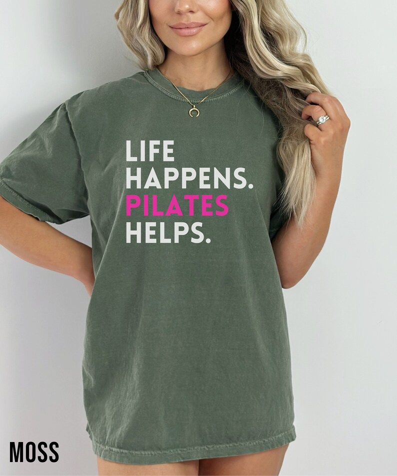 May include: A green t-shirt with the text "Life Happens. Pilates Helps." in white and pink lettering.