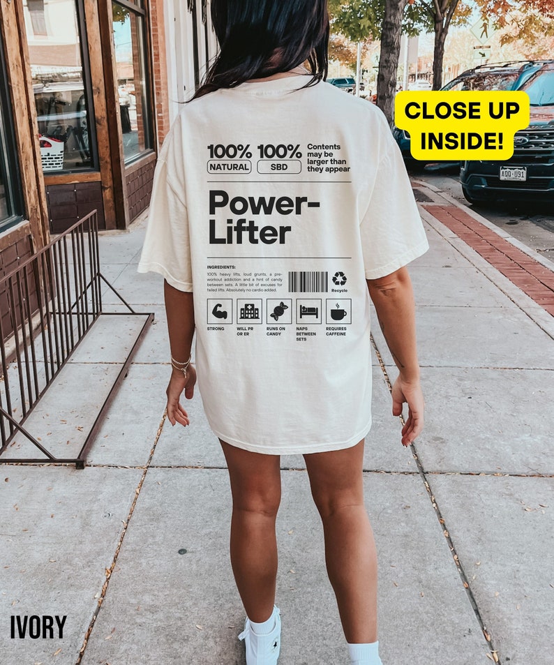May include: A white t-shirt with a black graphic design that says "100% 100% Natural SBD Power-Lifter" with a list of ingredients including "heavy lifts, loud grunts, a pre-workout addiction and a fist full of candy". The graphic also includes icons for strong, will PR, runs on candy, naps between sets, and requires caffeine.