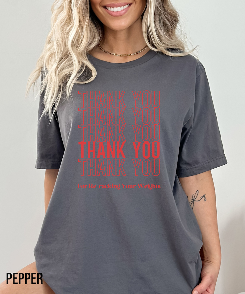 Peut inclure: T-shirt gris avec le texte "Thank You" r&eacute;p&eacute;t&eacute; plusieurs fois en rouge. Le texte "For Re-Racking Your Weights" est imprim&eacute; sous le texte r&eacute;p&eacute;t&eacute;.