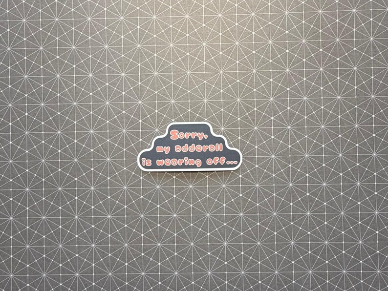 May include: A sticker in the shape of a cloud with the text "Sorry, my adderall is wearing off..." in red and white. The sticker is on a gray background with a white geometric pattern.